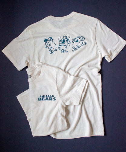 Forgotten and Refreshed: Chicago Bears monochrome double sided tee. Dark blue "Chicago Bears" text spans over the upper left chest. On the back, three dark blue bear characters preform various football motions (passing, running and blocking).